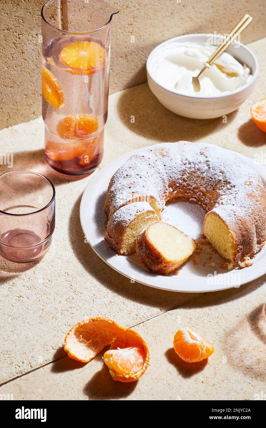 Grand angle de gâteau sucré appétissant arrosé de sucre en poudre placé près de la limonade mandarine Banque D'Images