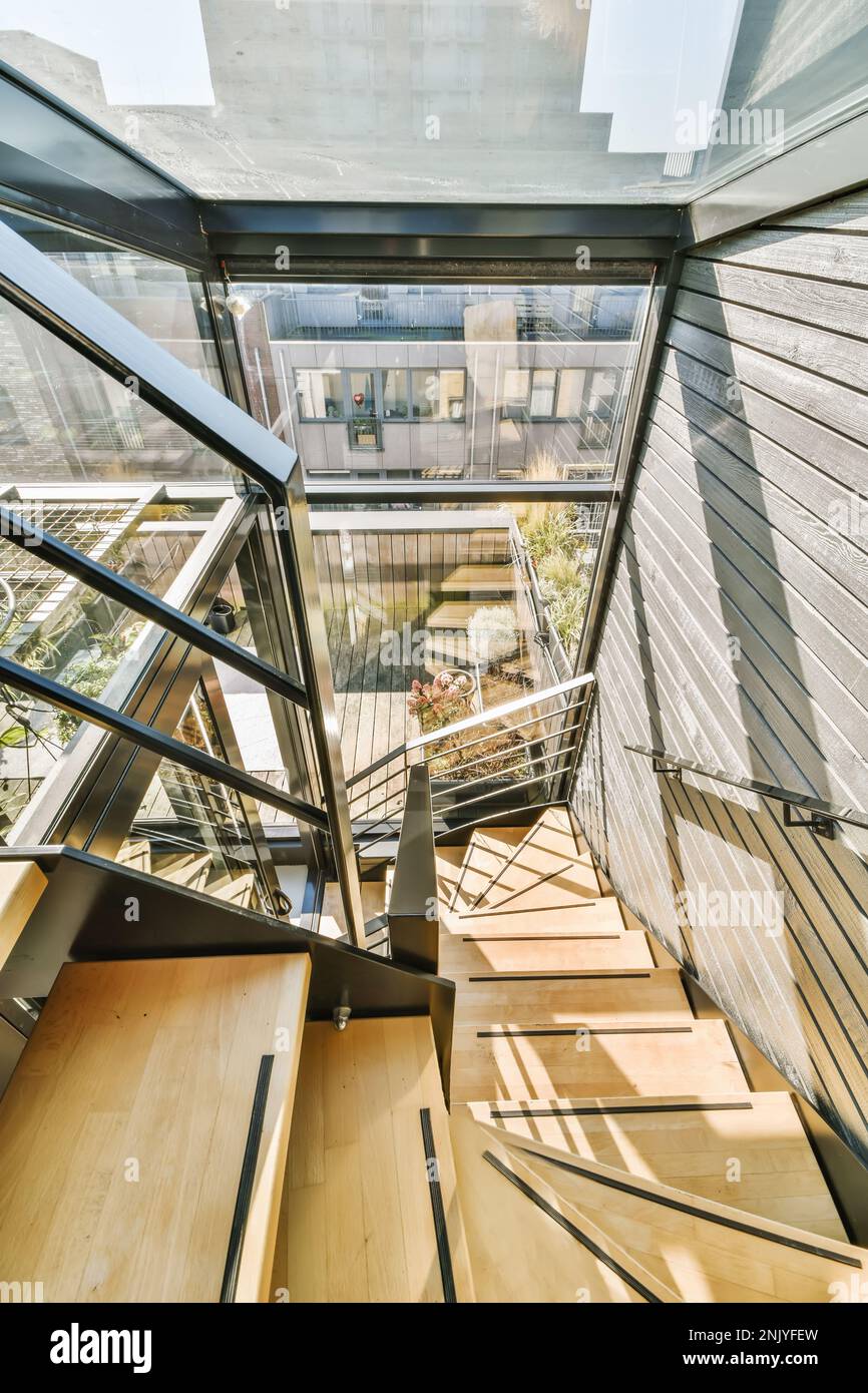 Depuis le dessus des escaliers à enrouleur en bois avec rambardes placées dans un bâtiment contemporain avec des murs en verre à la lumière du soleil Banque D'Images