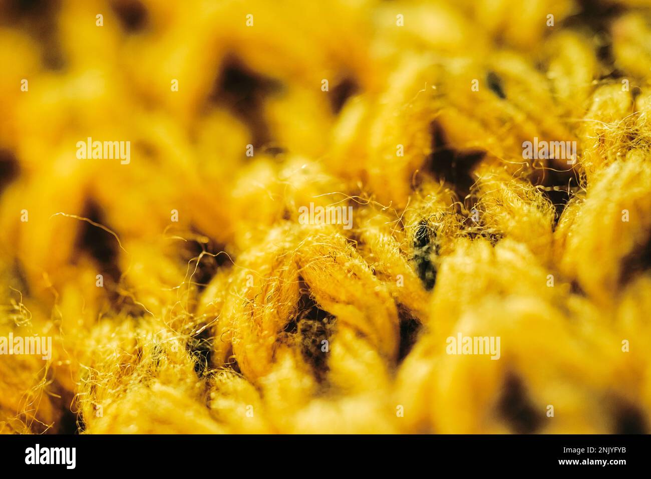 Gros plan plein cadre de chandail tricoté jaune vif avec texture de fil doux Banque D'Images