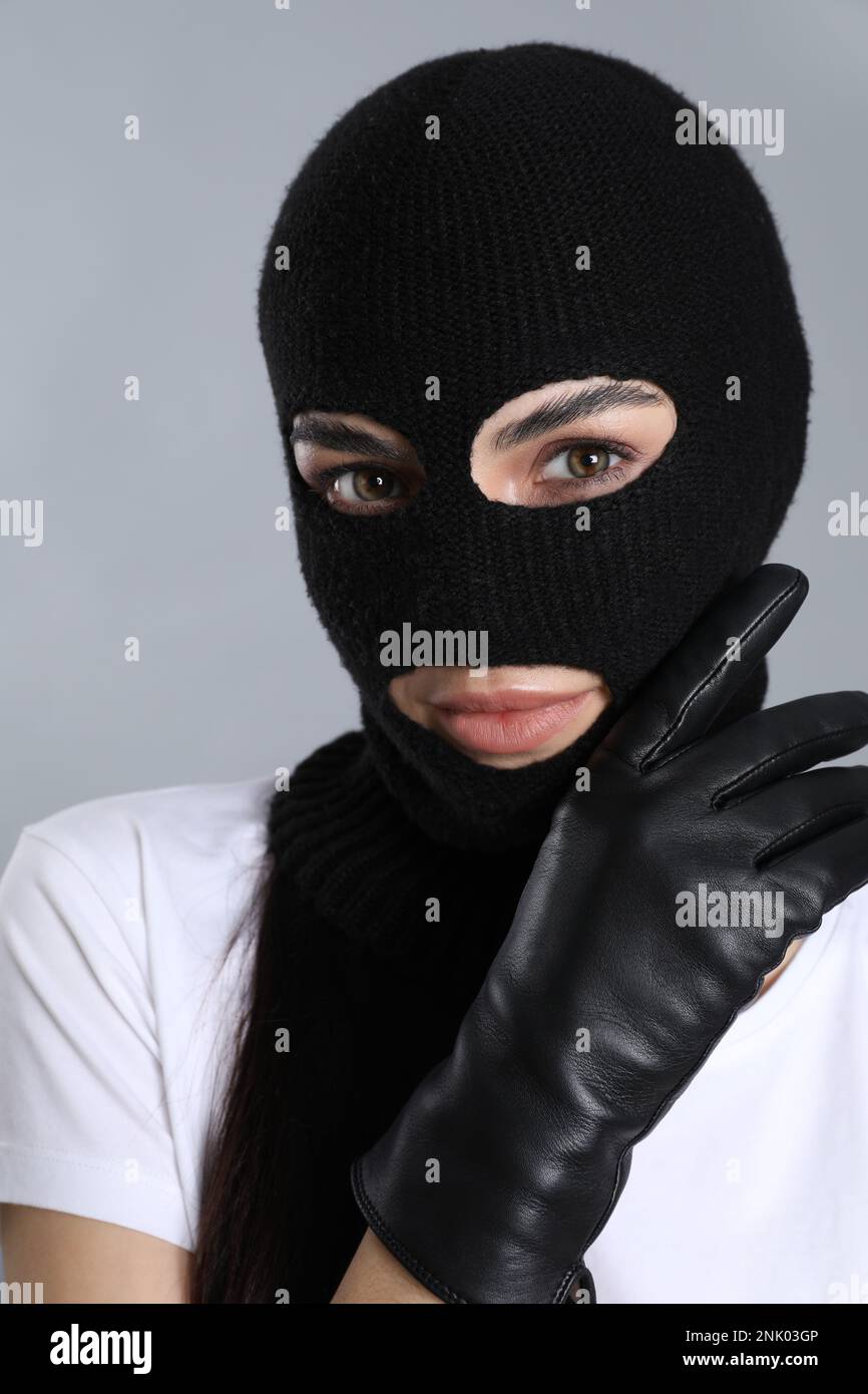 Femme portant une balaclava tricotée sur fond gris Banque D'Images