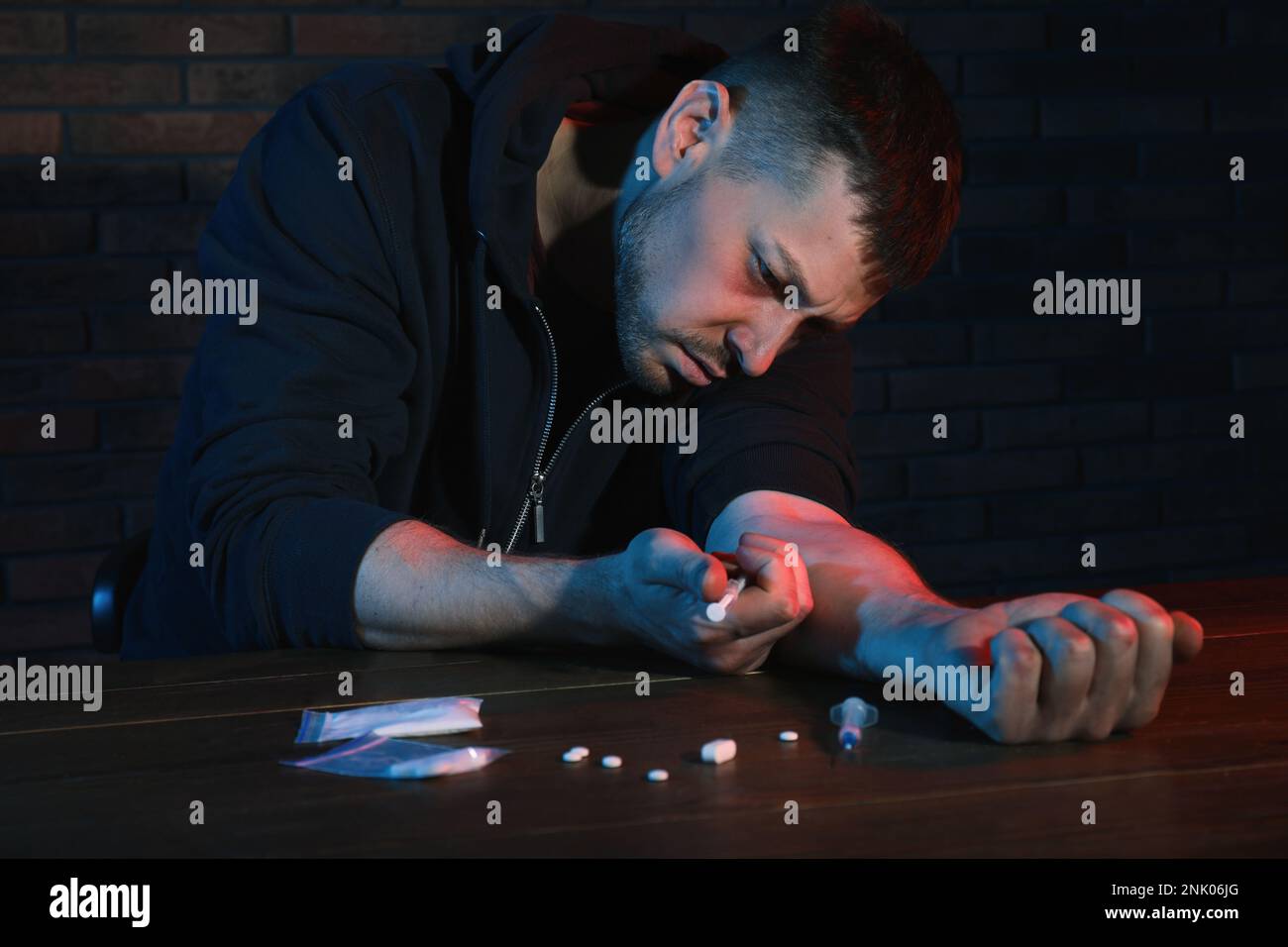 Homme accro prenant des drogues à la table à l'intérieur Banque D'Images