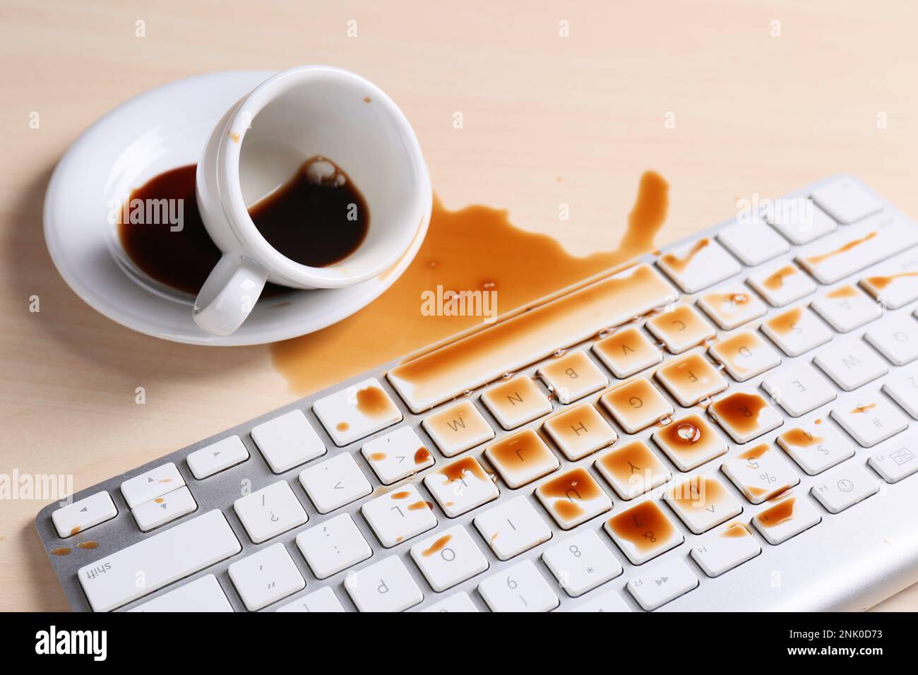Tasse de café renversée sur le clavier de l'ordinateur sur une table en bois Banque D'Images Tasse de café renversée sur le clavier de l'ordinateur sur une table en bois Banque D'Images