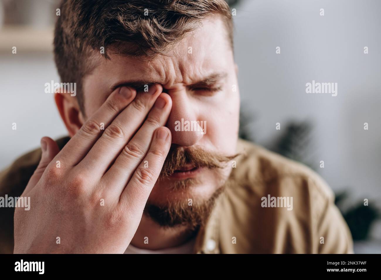 Foyer sélectif d'un homme caucasien triste et frustré souffrant de fortes douleurs oculaires. Problème de vue. Jeune homme barbu 30s touchant les yeux se sentant d Banque D'Images