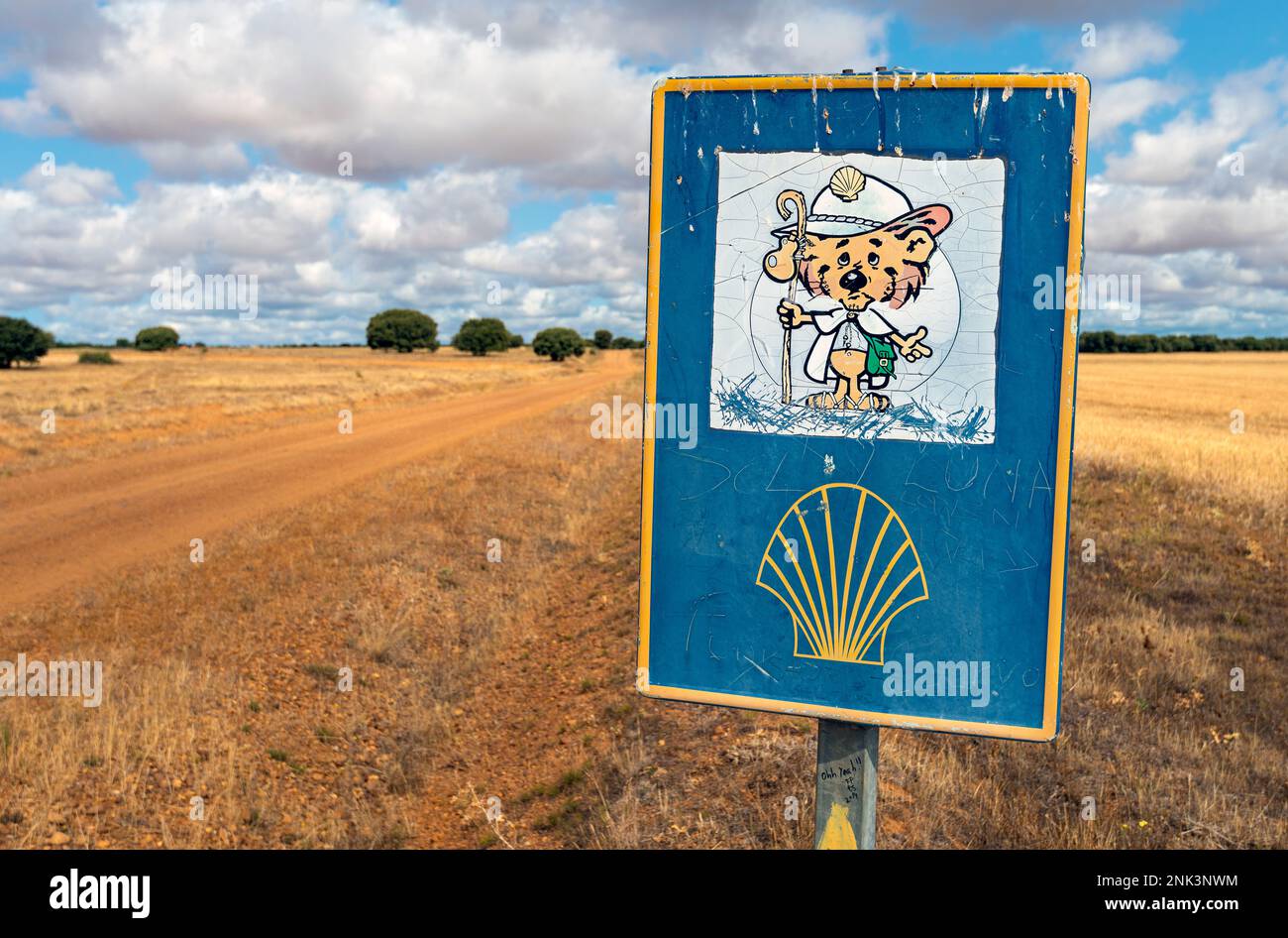 Un panneau bleu marquant le chemin de pèlerinage du Camino de Santiago se dresse sur le côté d'un chemin de terre dans la campagne espagnole Banque D'Images