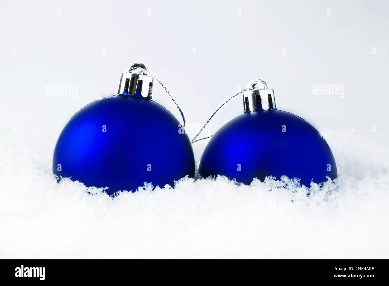 Décorations de Noël. Boules de Noël bleues sur neige pendant une chute de neige, sur fond de bokeh gris argenté. Carte de Noël - concept. Sélectif FO Banque D'Images