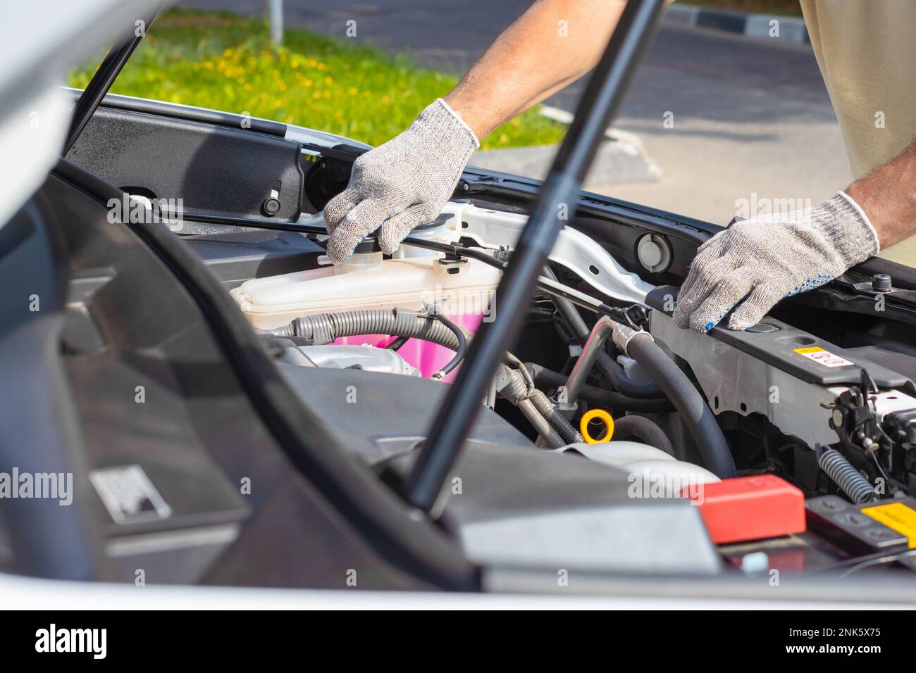 le conducteur de la voiture vérifie le réservoir de liquide de refroidissement. conducteur effectuant des réparations. liquide de refroidissement pour moteur de voiture. réparation de voiture de service Banque D'Images
