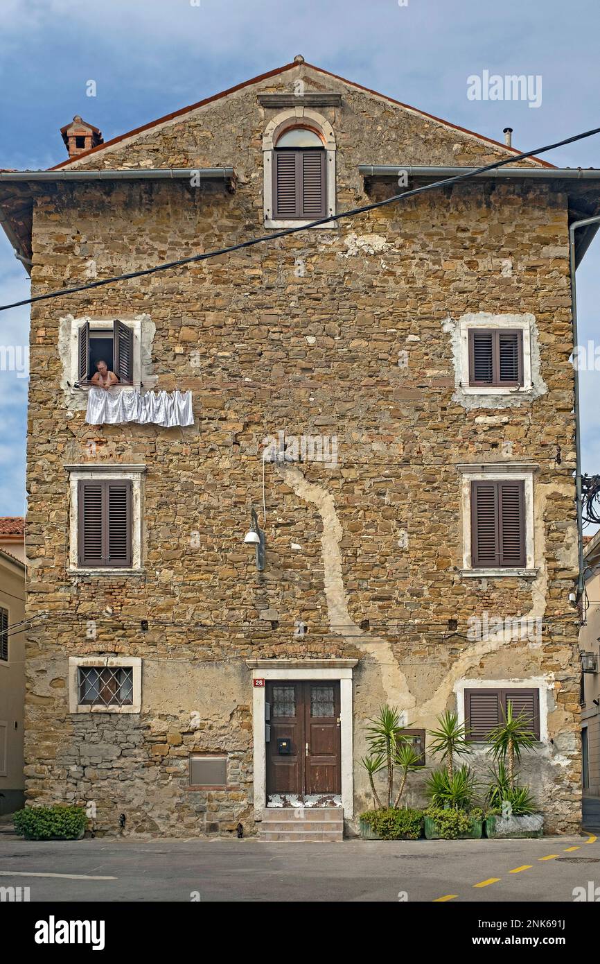 Femme dans la vieille maison pendante vêtements sur la ligne de lavage dans la ville Koper / Capodistria, péninsule d'Istrie, Obalnokraška, littoral / Primorska, Slovénie Banque D'Images