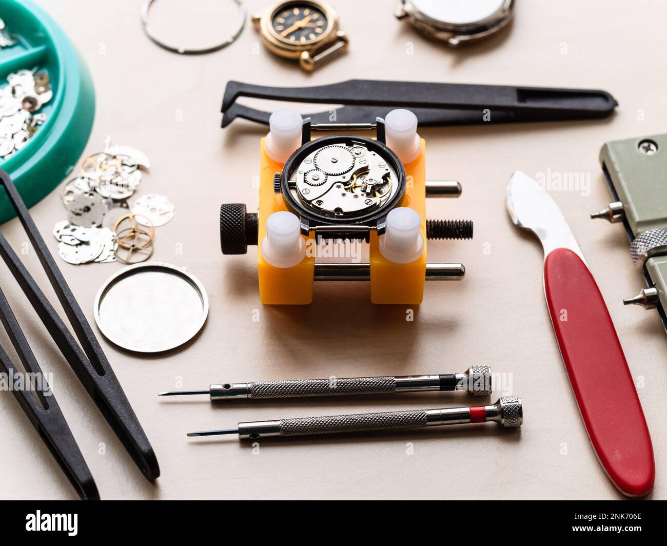 ouvrir la montre mécanique dans le support jaune et les outils sur la table en bois dans l'atelier horloger Banque D'Images