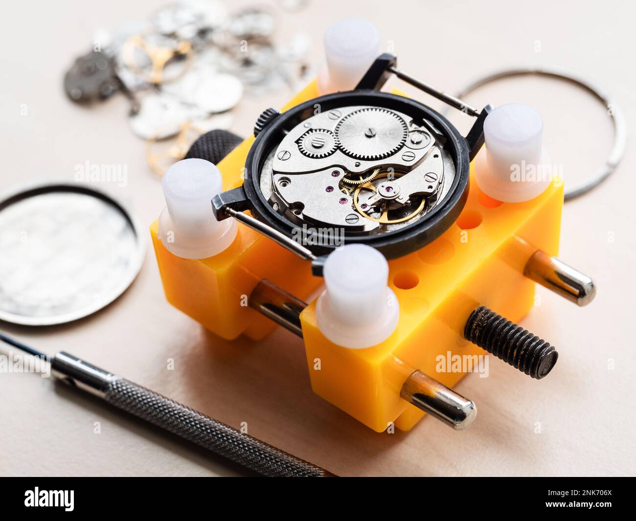 ancienne montre mécanique dans support jaune gros plan sur une table en bois dans l'atelier horloger Banque D'Images
