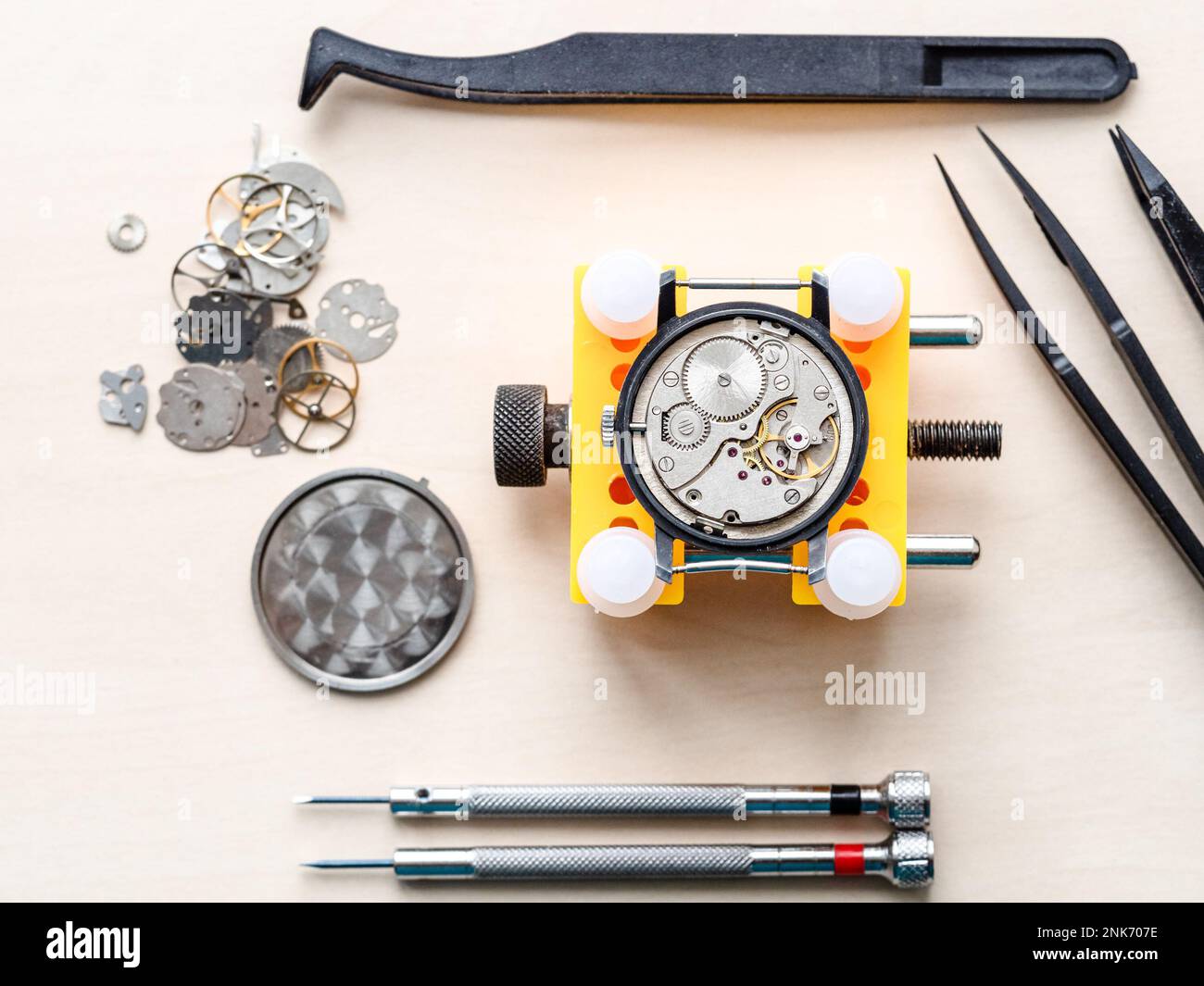 vue de dessus de la montre ouverte dans le support jaune et des outils sur une table en bois dans l'atelier horloger Banque D'Images