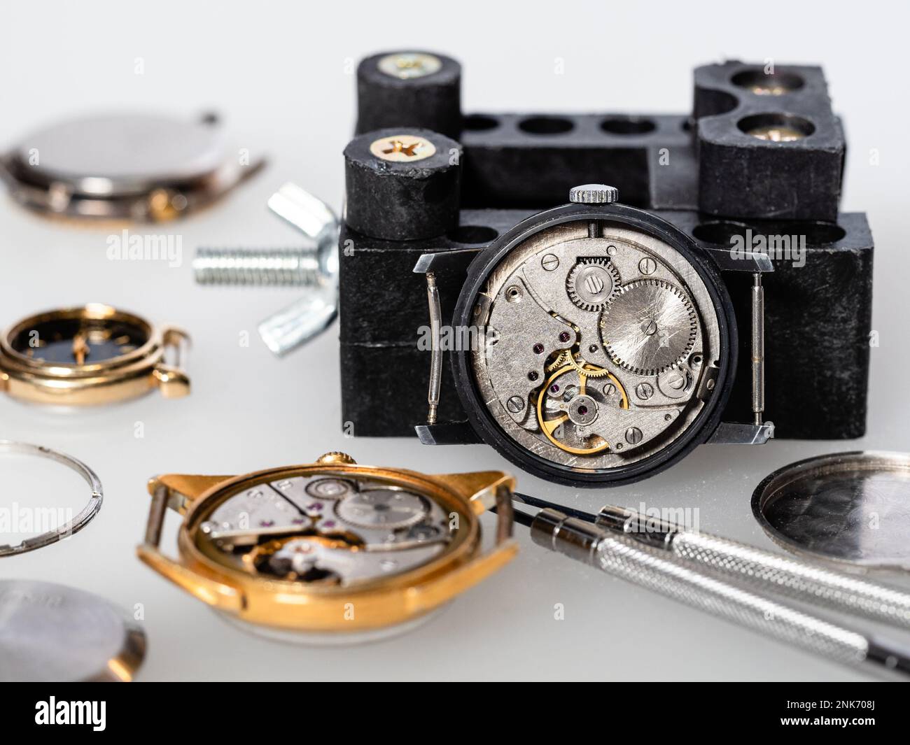 vieilles montres mécaniques ouvertes et tournevis sur panneau blanc dans l'atelier horloger Banque D'Images