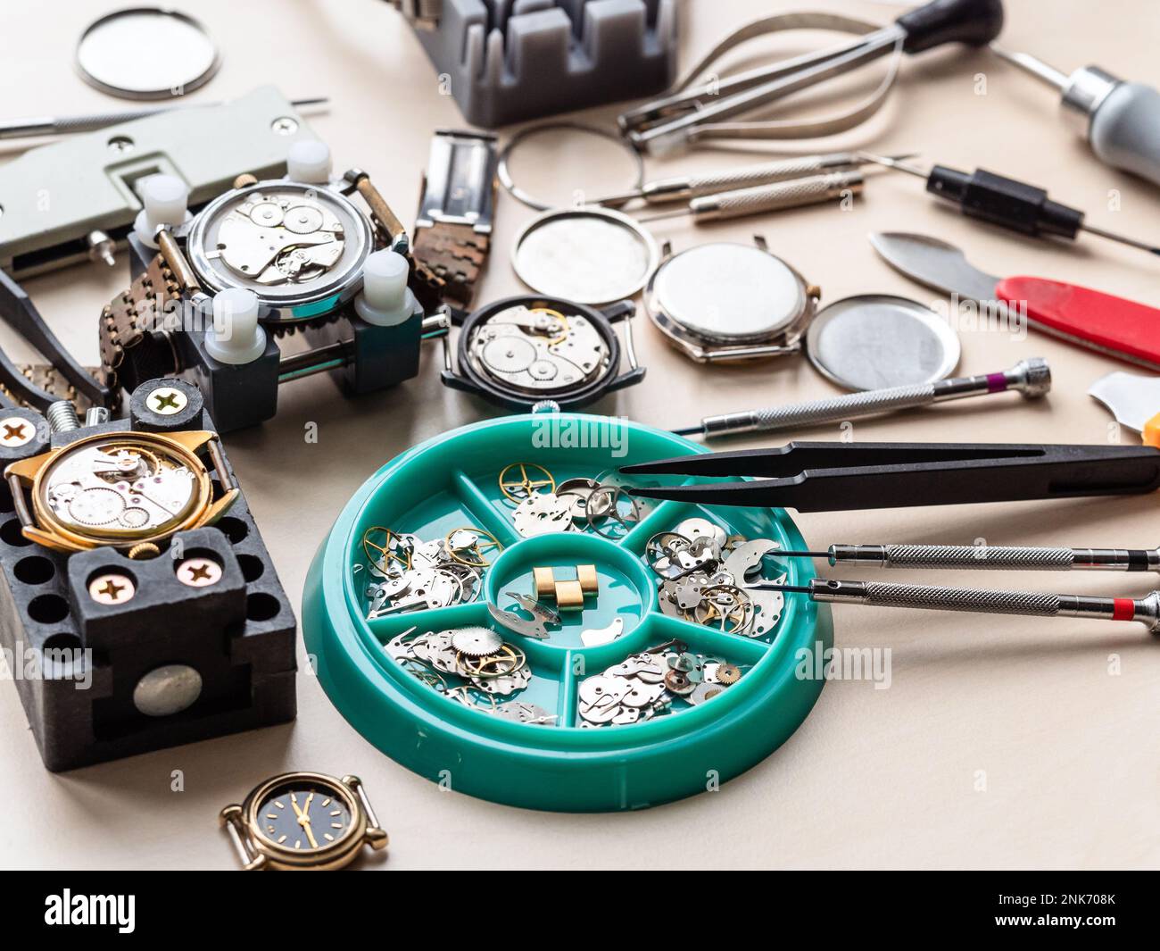 horloge pièces de rechange dans plateau, outils et montres ouvertes sur table en bois dans l'atelier horloger Banque D'Images