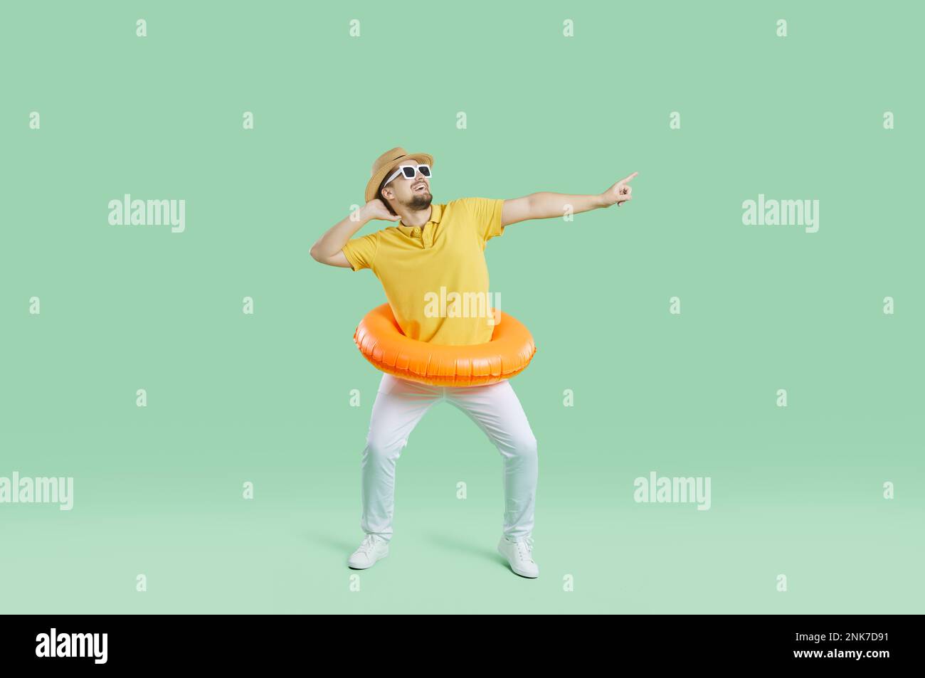 Drôle homme gai avec cercle gonflable pour la natation ayant le plaisir sur fond vert clair. Banque D'Images