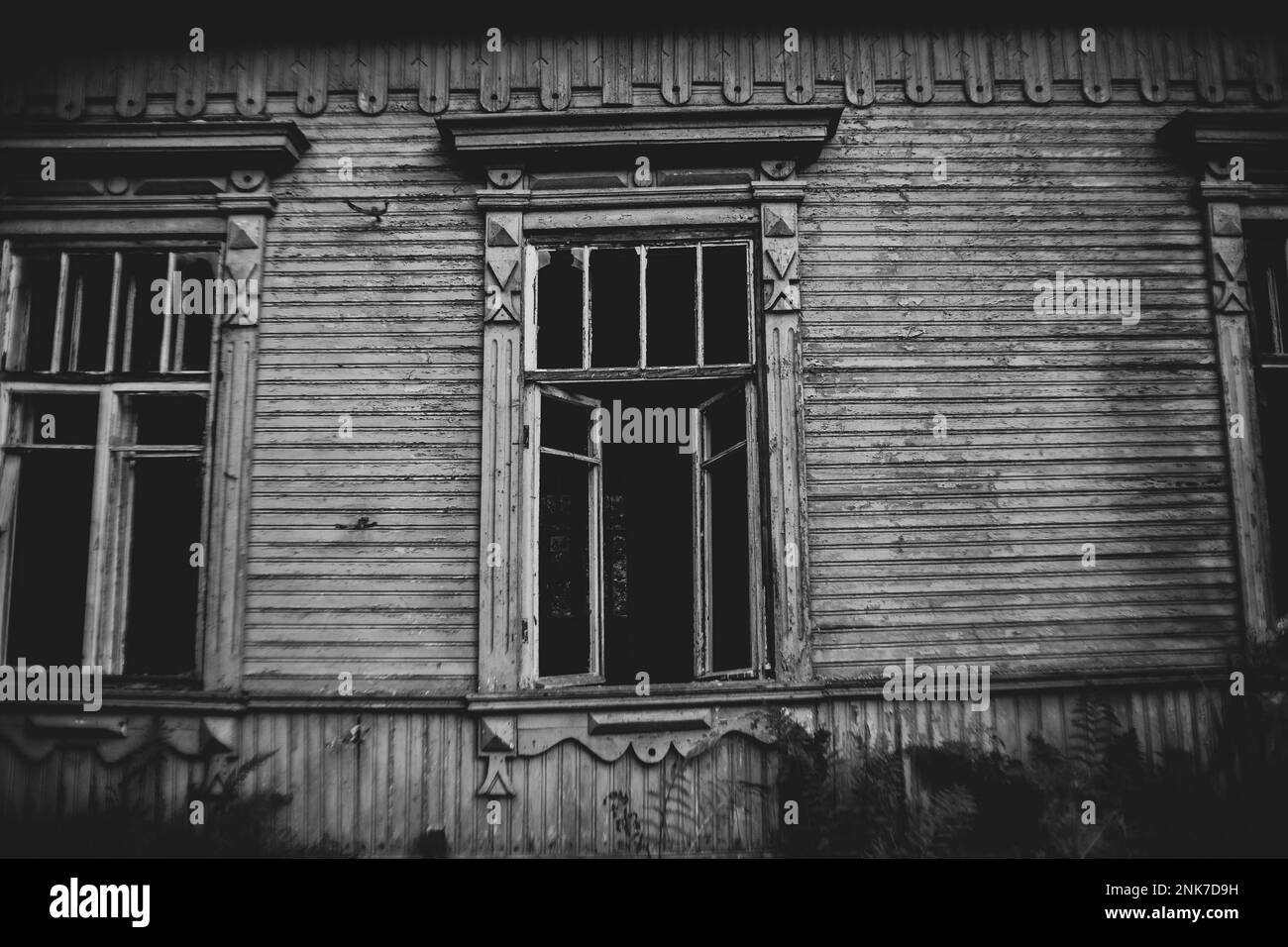 Une image en noir et blanc d'un vieux village en bois abandonné maison avec des fenêtres cassées vides. Halloween. Horreur et horreur. La maison maudite. Banque D'Images