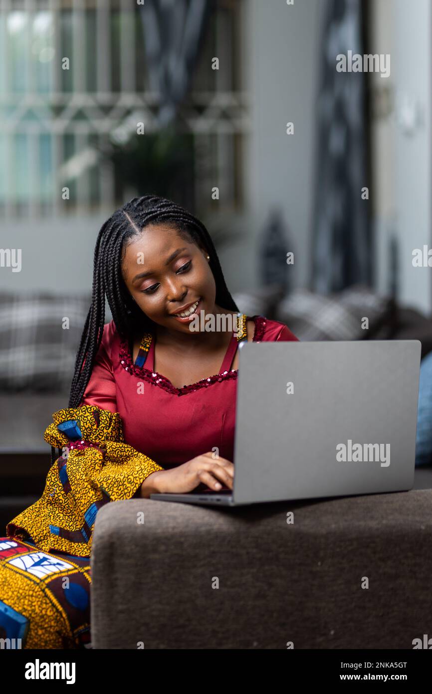 Jeune femme africaine travaillant à la maison avec son ordinateur portable. Banque D'Images