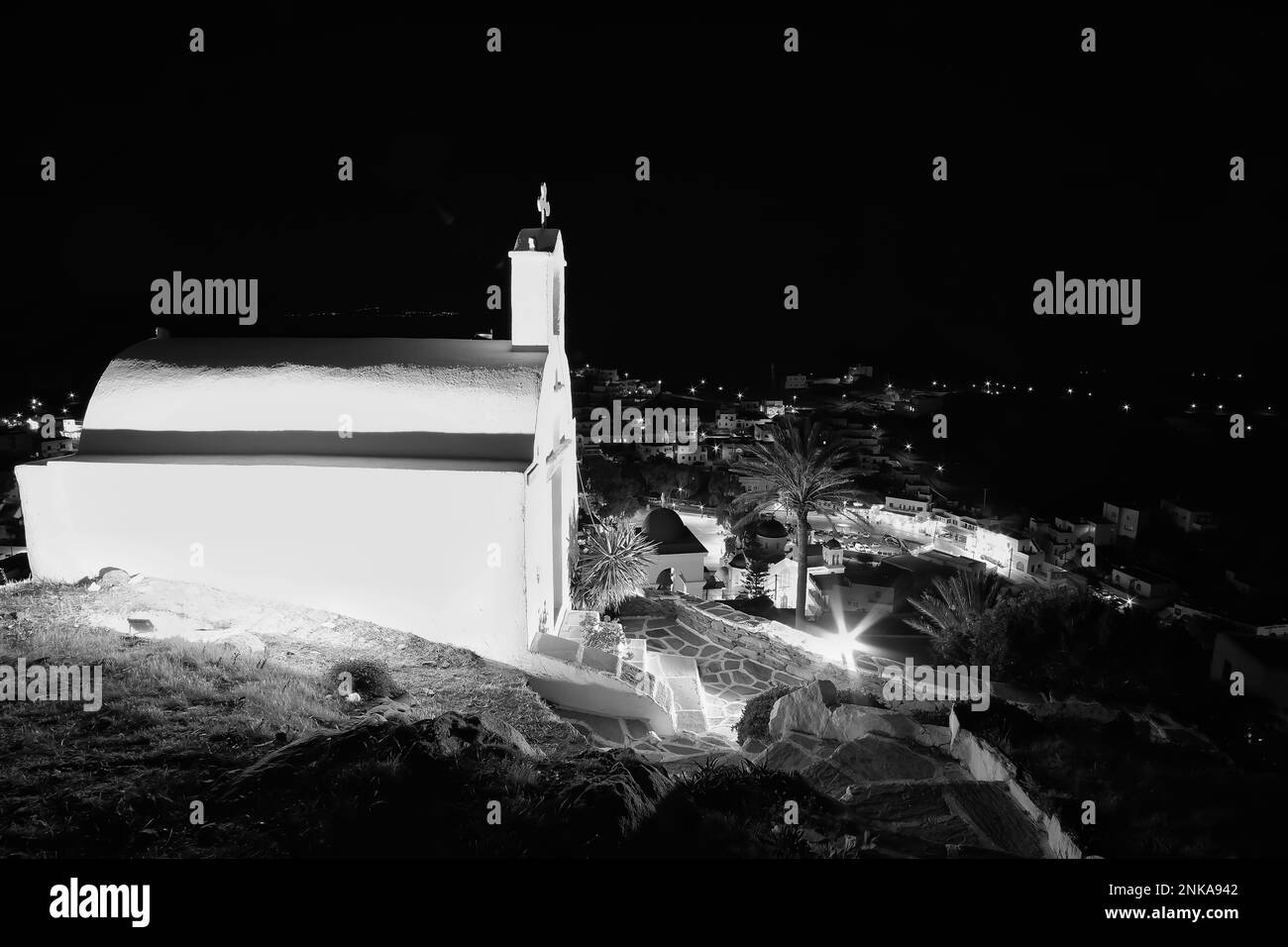 Vue sur une petite église blanchie à la chaux illuminée dans iOS Grèce au sommet de la colline Banque D'Images