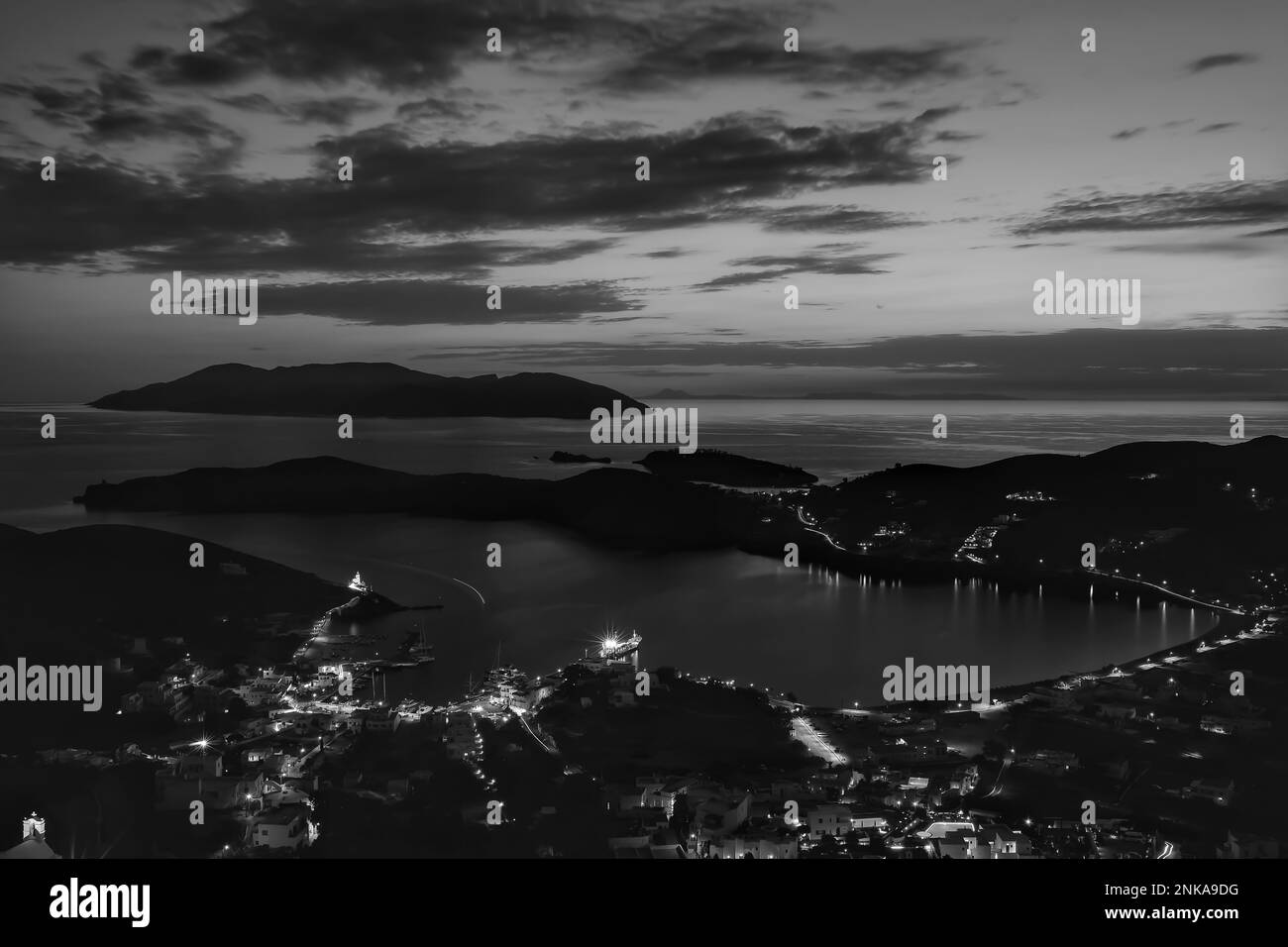 Vue panoramique sur le pittoresque port lumineux d'iOS en Grèce tandis que le soleil se couche de façon spectaculaire en noir et blanc Banque D'Images