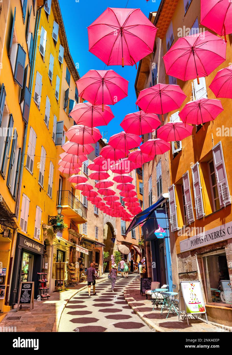 Grasse, France - 6 août 2022: Maisons de tenement historique et rues étroites décorées de parasols roses de la vieille ville de parfumerie ville de GR Banque D'Images