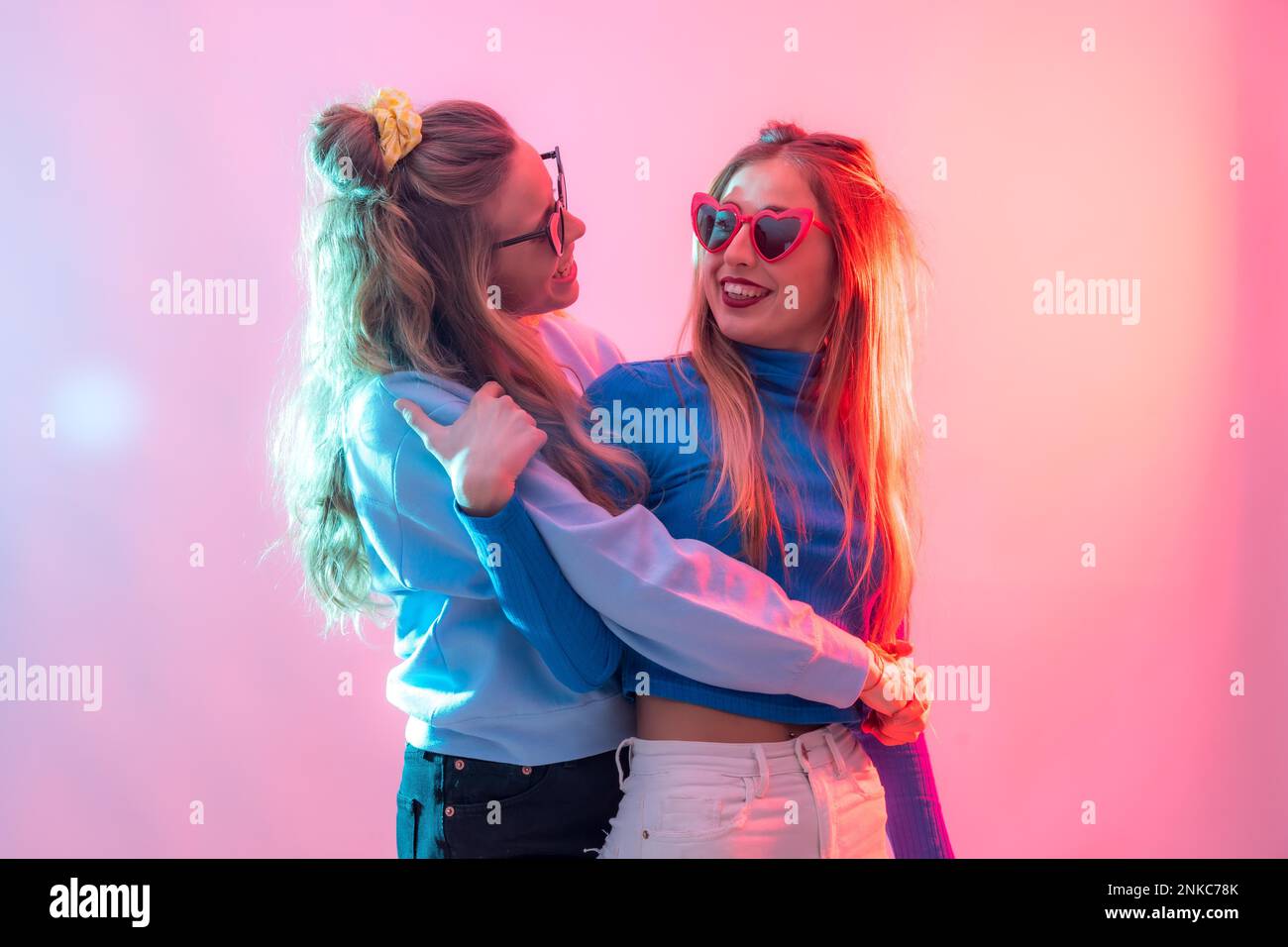 Deux jeunes femmes blanches blondes dansant dans la boîte de nuit, s'embrassant les unes les autres pour danser en fête Banque D'Images