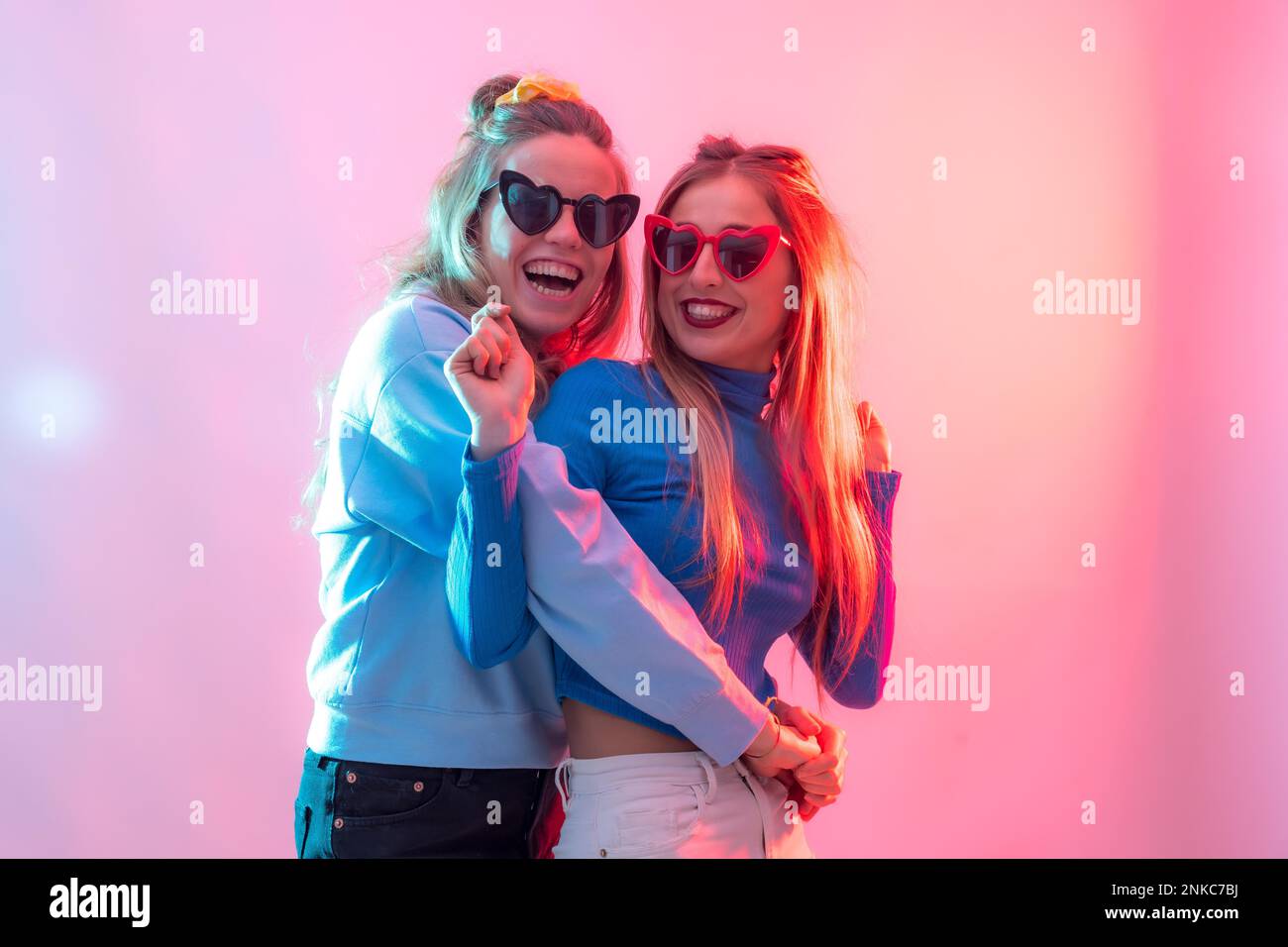 Deux jeunes femmes blanches blondes dansant dans la boîte de nuit, s'embrassant les unes les autres pour danser en fête Banque D'Images