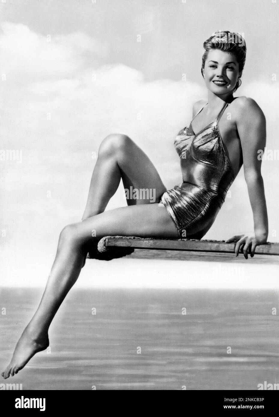 1953 environ : L'actrice américaine ESTHER WILLIAMS , Ppubblicity STILL - CINÉMA - portrait - ritrato - jambes - gambe - posture leggy - PIN UP - sourire - sorriso - costume da bagno dorato argento - argento - oro - maillot de bain robe or argent - trampolino - chignon - spalla - spalle - épaules -- -- Archivio GBB Banque D'Images