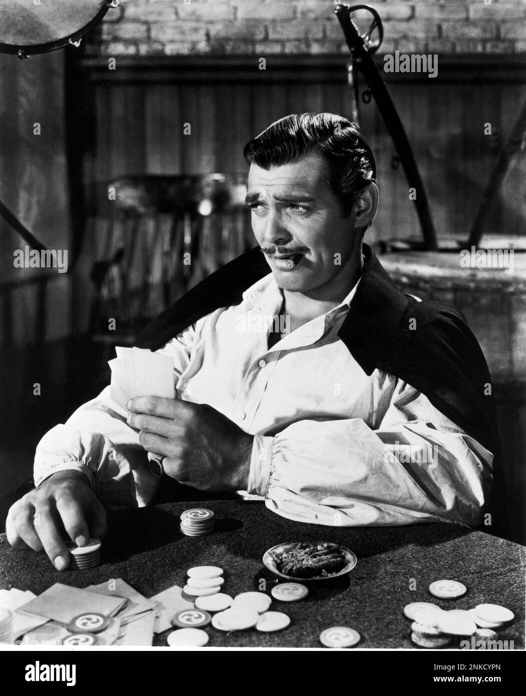 1939 : l'acteur Clark PIGNON en PARTI AVEC LE VENT ( via col vento ) Par Victor Fleming - CINÉMA - FILM - - baffi - moustache - sigaro - cigare - personalità celeità la fumatore - fumeur - célébrités personnalités personnalités acteurs - ring - anello - giocatore di carte - carte da gioco - cartes de jeu - cartes de jeu - joueur - Fiches - POKER - chemise blanche - camacia bianca - brillantina - graisse --- Archivio GBB Banque D'Images