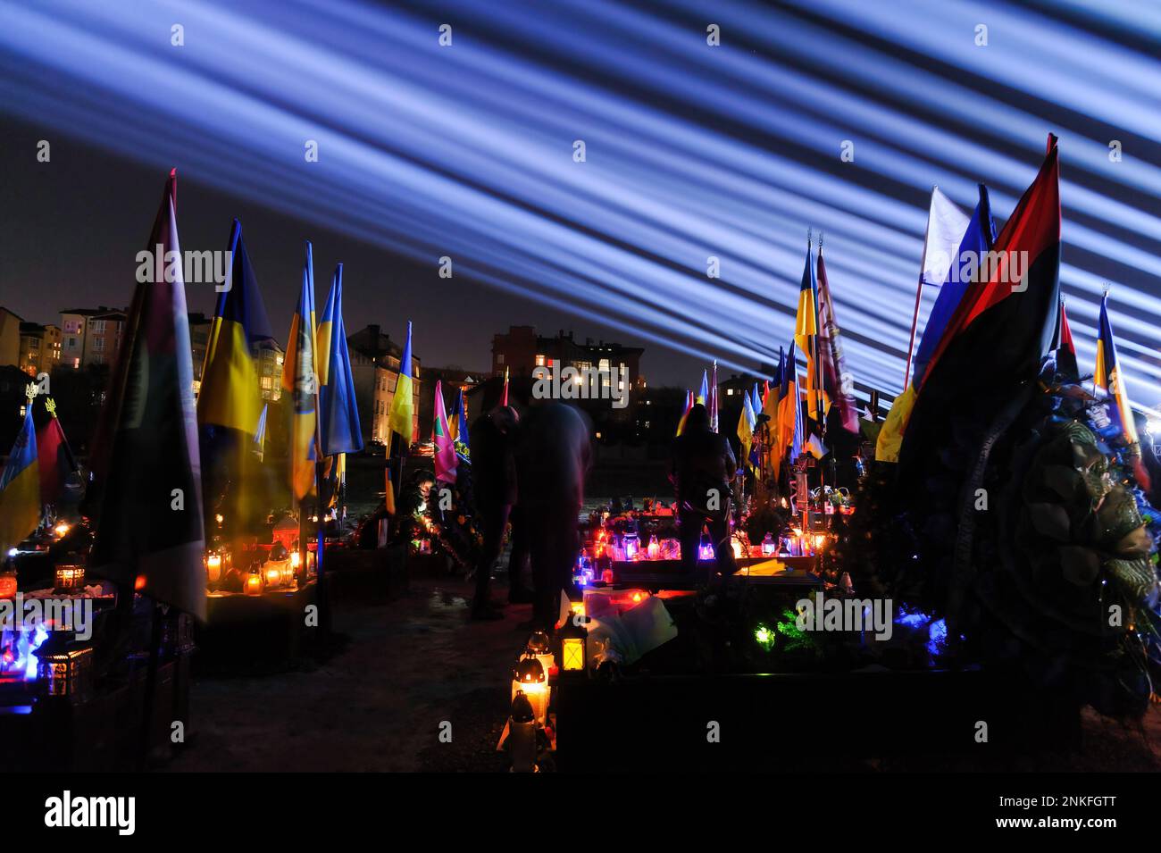 Lviv, Ukraine. 23rd févr. 2023. Les gens visitent les tombes des soldats tombés au cimetière du champ de Lychakiv où des centaines de soldats ukrainiens morts au cours de la dernière année sont enterrés lors d'un événement de commémoration alors que des « rayons de mémoire » symboliques ont été illuminés au cimetière militaire de Lychakiv pour marquer le premier anniversaire de La guerre de la Russie contre l'Ukraine. La Russie a envahi l'Ukraine le 24 février 2022, déclenchant la plus grande attaque militaire en Europe depuis la Seconde Guerre mondiale Crédit : SOPA Images Limited/Alamy Live News Banque D'Images