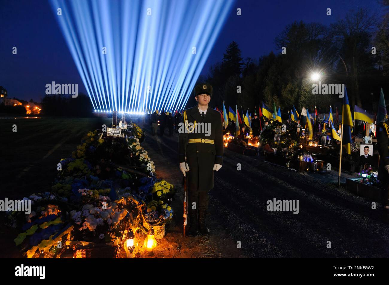 Lviv, Ukraine. 23rd févr. 2023. Un soldat se tient à un événement de commémoration des soldats tombés au cimetière de Field of Lychakiv où des centaines de soldats ukrainiens morts au cours de la dernière année sont enterrés au cours d'un événement de commémoration alors que des « rayons de mémoire » symboliques ont été illuminés au cimetière militaire de Lychakiv pour marquer le Premier anniversaire de la guerre de la Russie contre l'Ukraine. La Russie a envahi l'Ukraine le 24 février 2022, déclenchant la plus grande attaque militaire en Europe depuis la Seconde Guerre mondiale Crédit : SOPA Images Limited/Alamy Live News Banque D'Images