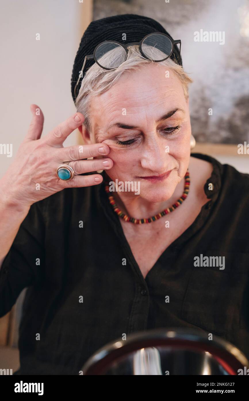 Femme âgée massant le visage à la maison Banque D'Images