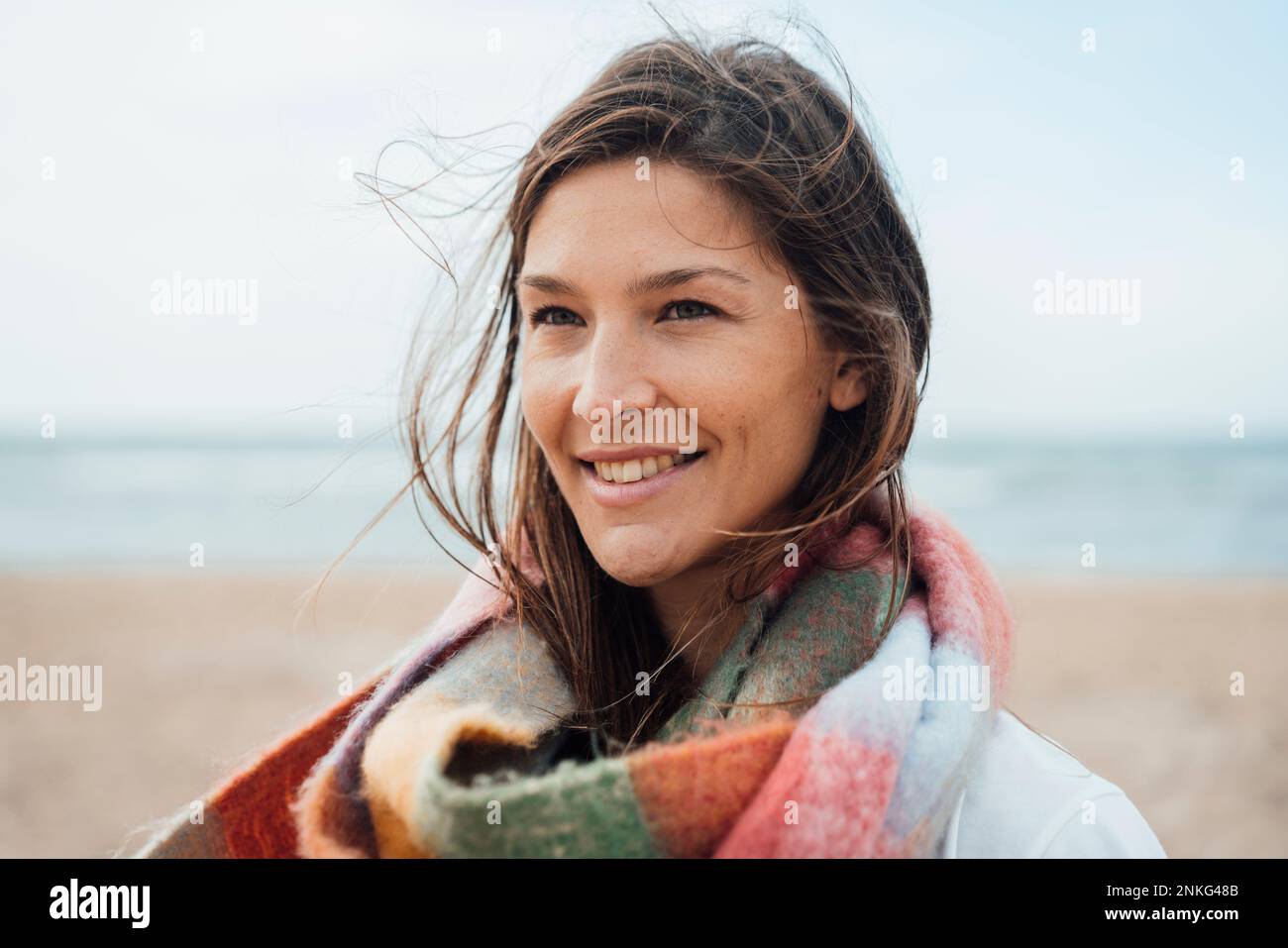 Femme contemplative avec foulard à la plage Banque D'Images