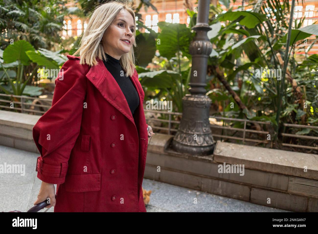 Femme mature en manteau long rouge marchant sur le sentier Banque D'Images