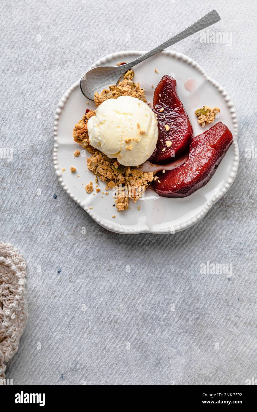 Assiette de poires au vin rouge avec crème glacée et granola Banque D'Images