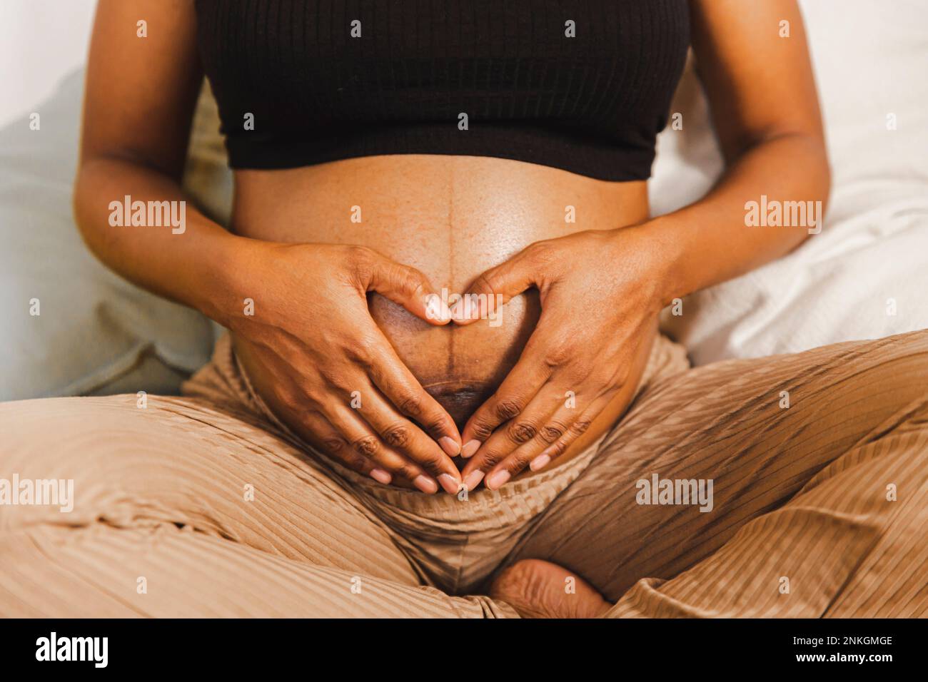 Femme enceinte en forme de coeur avec les mains sur le ventre Banque D'Images