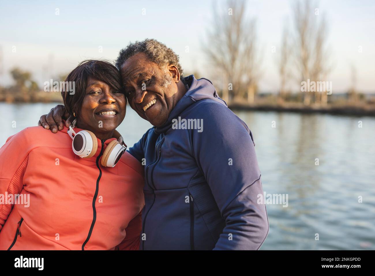 Couple senior heureux devant le lac au coucher du soleil Banque D'Images