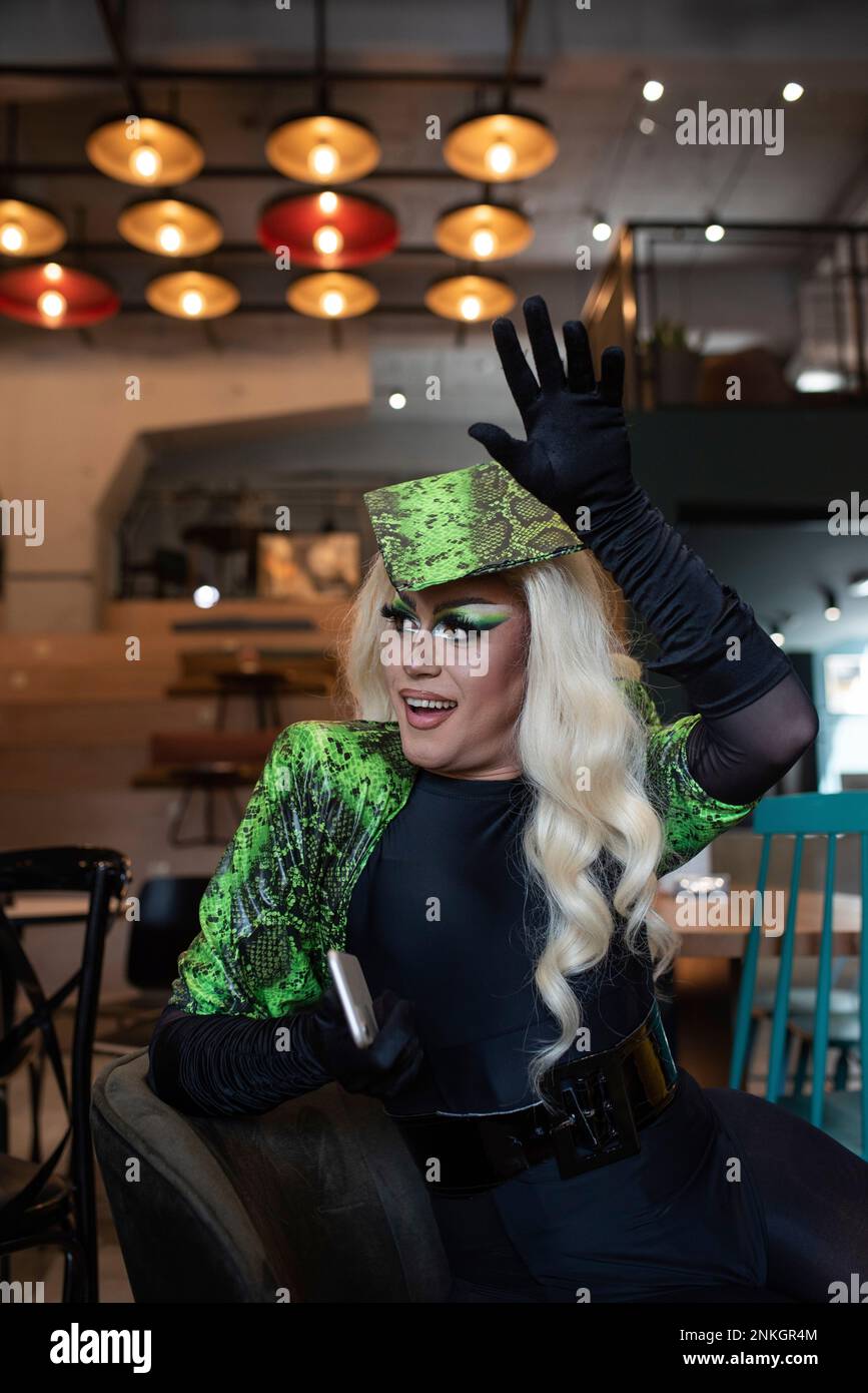 Jeune homme androgyne avec un smartphone agitant dans un café Banque D'Images