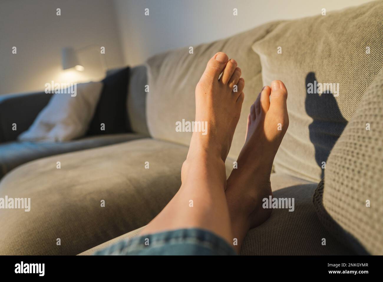 Jambes de femme reposant sur un canapé Banque D'Images