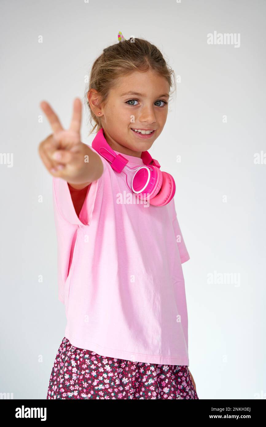 Fille souriante montrant le signe de paix sur fond blanc Banque D'Images