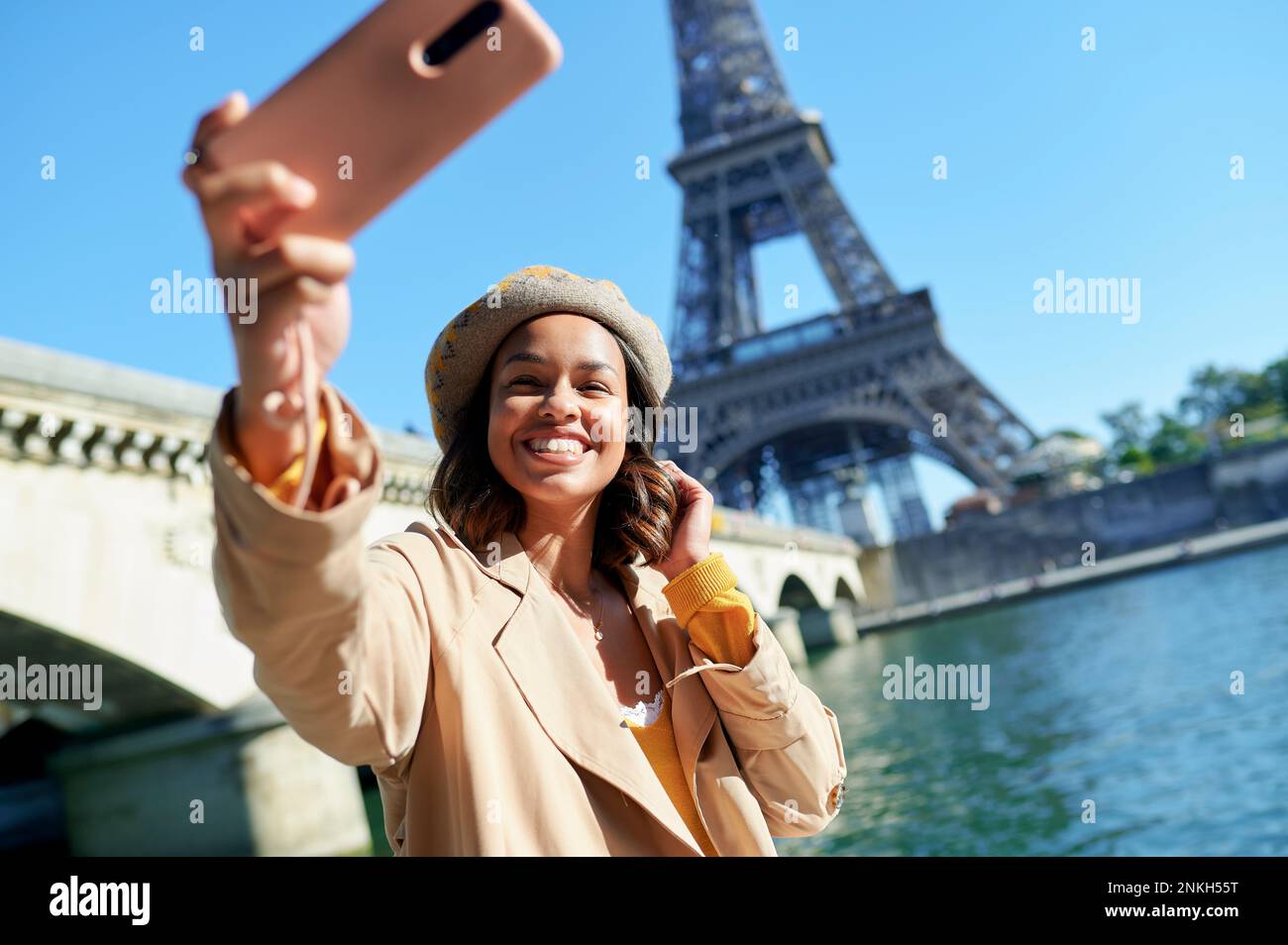 Bonne jeune femme qui prend le selfie à travers un smartphone en face de la tour Eiffel, Paris, France Banque D'Images