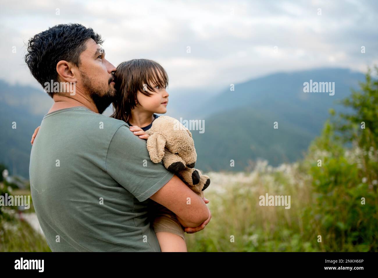 Père transportant son fils avec ours en peluche en vacances Banque D'Images