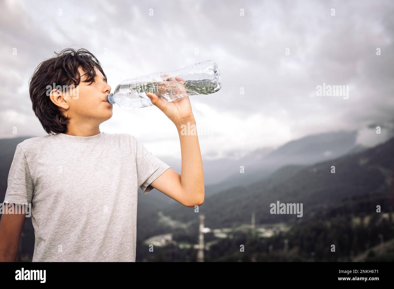 Un garçon assoiffé boit de l'eau de la bouteille Banque D'Images