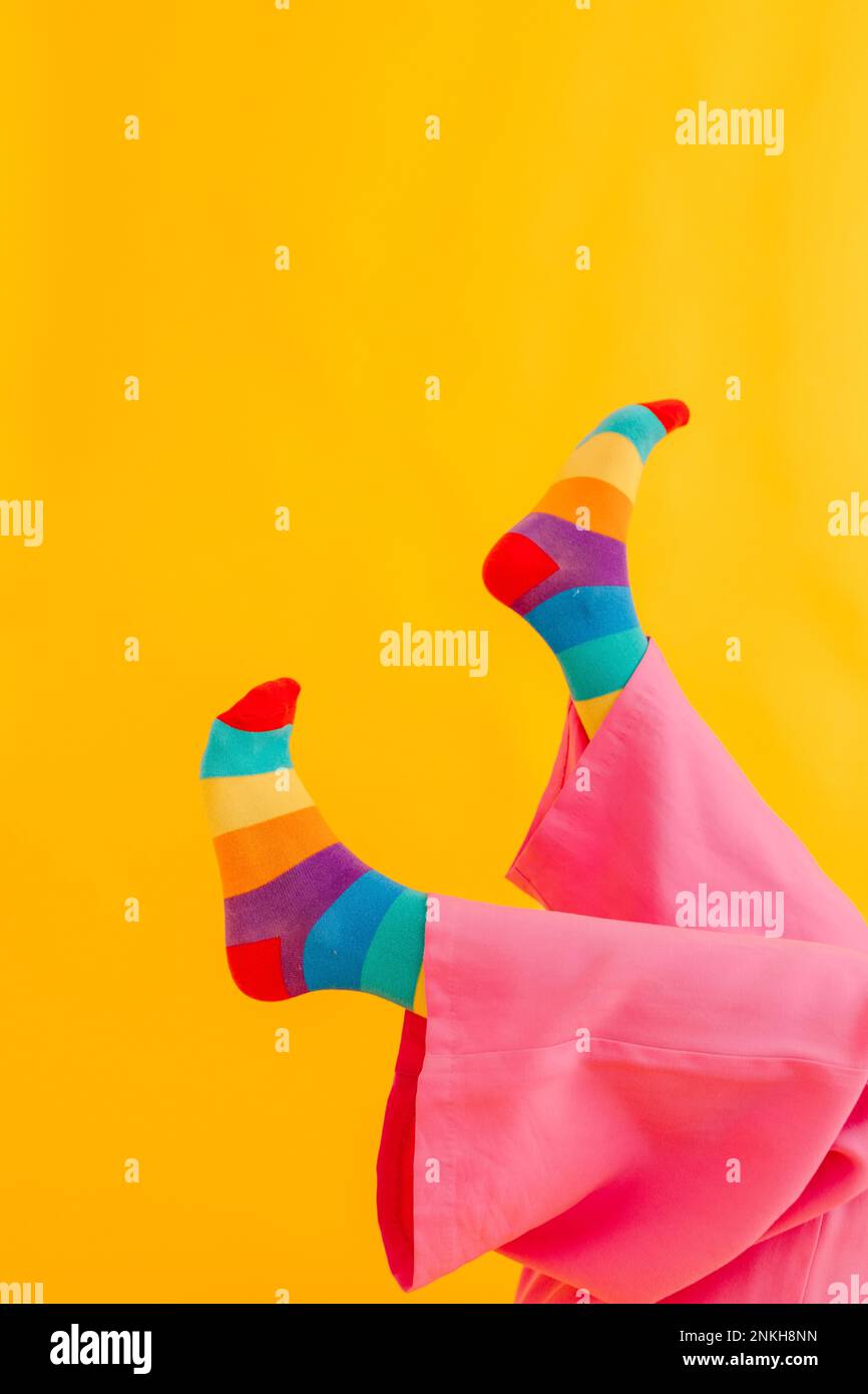 Pieds de femme avec chaussettes de couleur arc-en-ciel sur fond jaune Banque D'Images