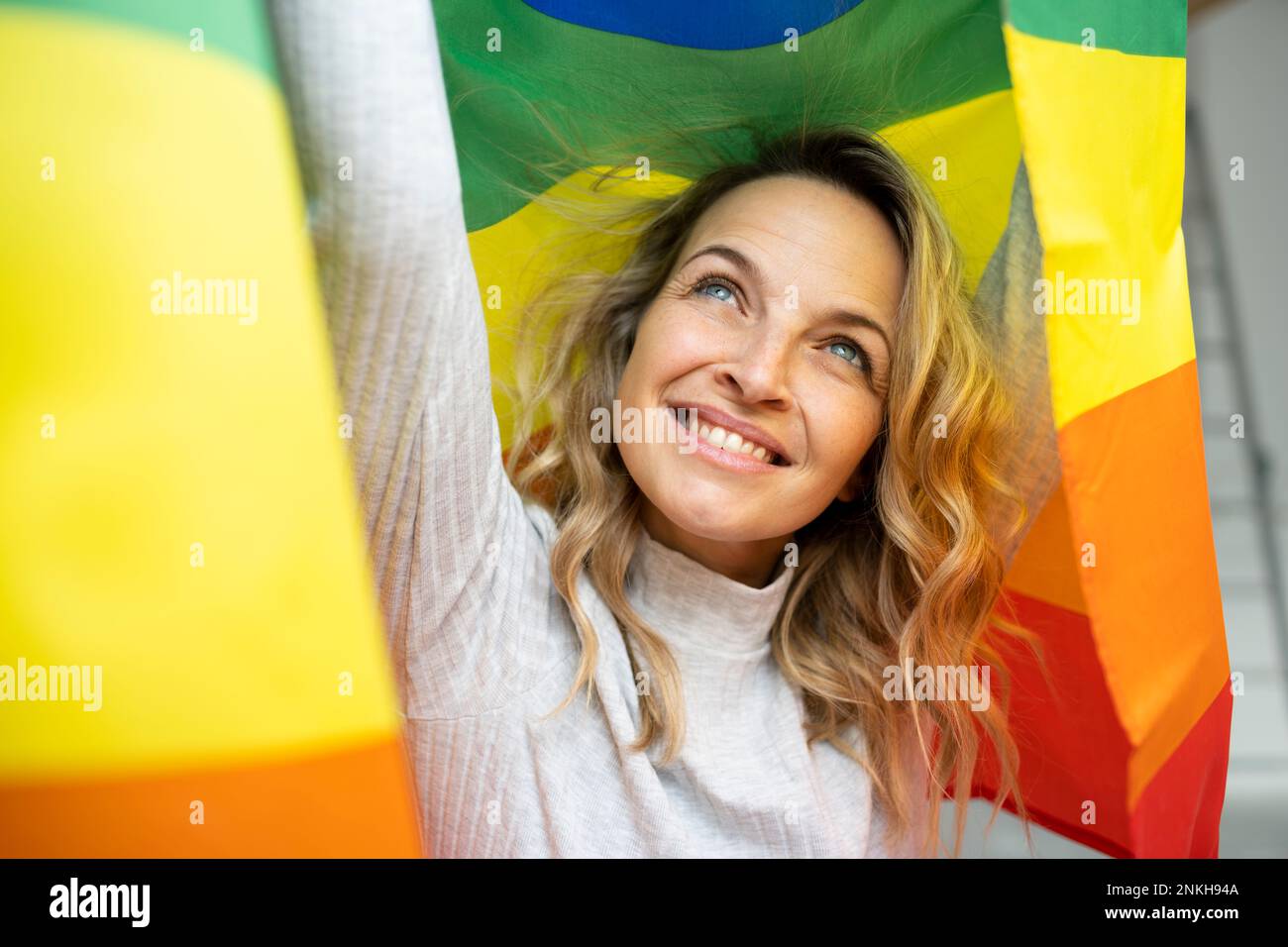 Bonne femme mûre avec les bras levés tenant le drapeau coloré Banque D'Images