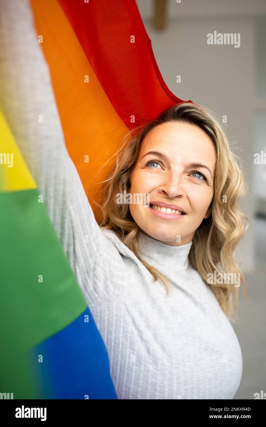 Femme mûre souriante portant un drapeau multicolore Banque D'Images