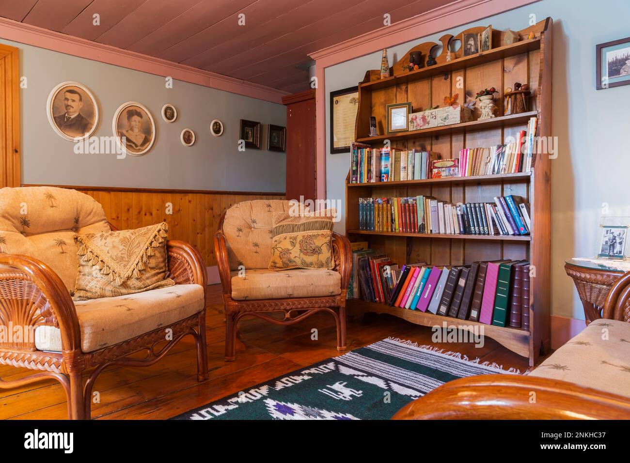 Fauteuils en rotin et bibliothèque en pin dans le salon à l'étage à l'intérieur de la vieille maison datant de 1840. Banque D'Images