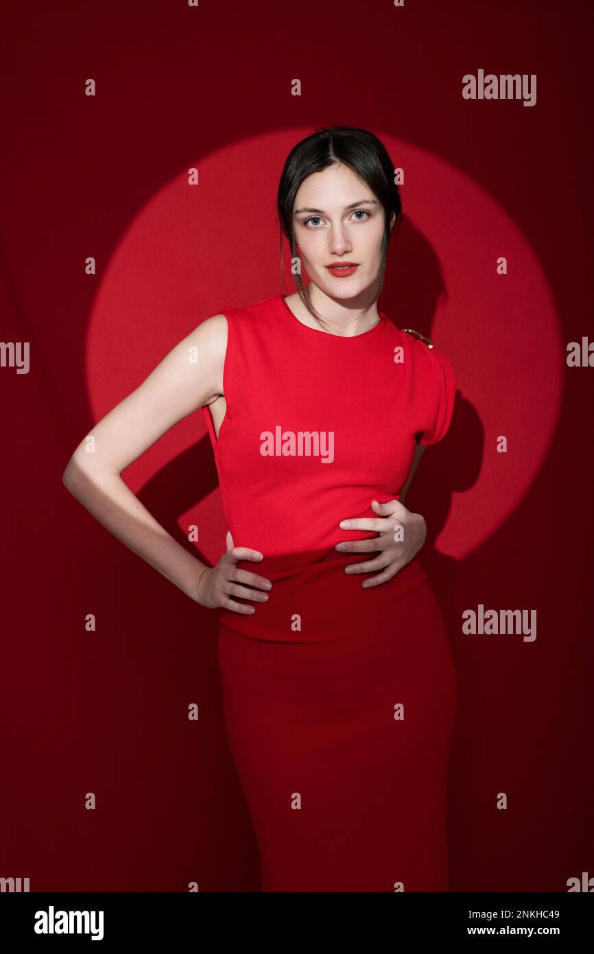 Femme pleine de confiance avec les mains sur les hanches sur fond rouge Banque D'Images