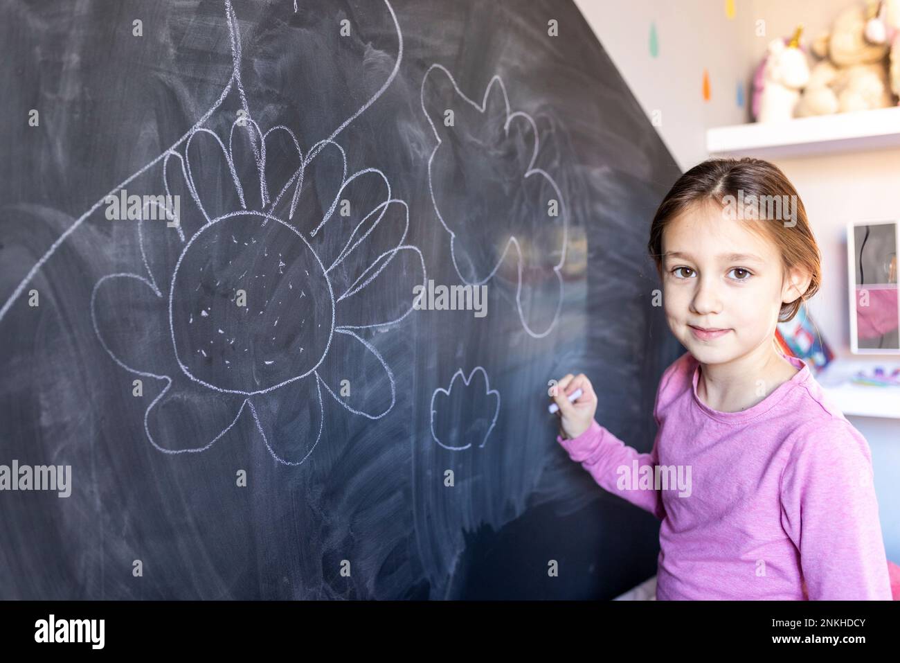 Fille souriante avec dessin à la craie à bord à la maison Banque D'Images