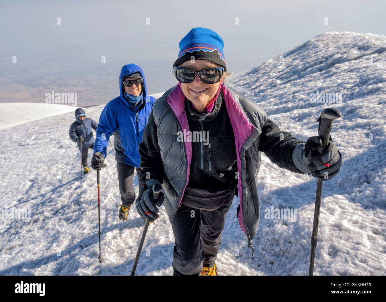Des randonneurs souriants trekking sur une montagne enneigée le week-end Banque D'Images