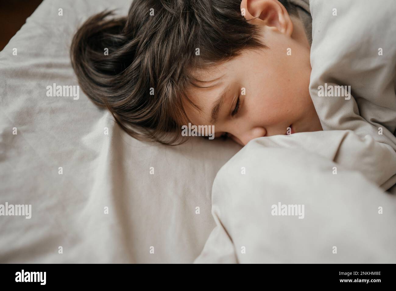 Le garçon endormi sur le lit chez lui Banque D'Images