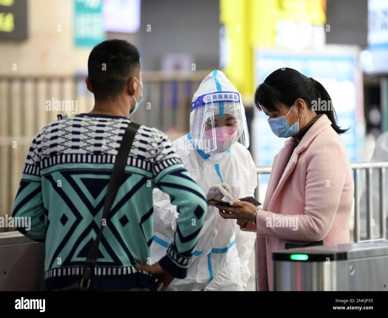 A worker in PPE checks the codes of Covid-19 risk of a traveler at a railway station in Nanchang city in central China's Jiangxi province Sunday, March 13, 2022. Two coronavirus carriers have been found in the city. (FeatureChina via AP Images) Banque D'Images