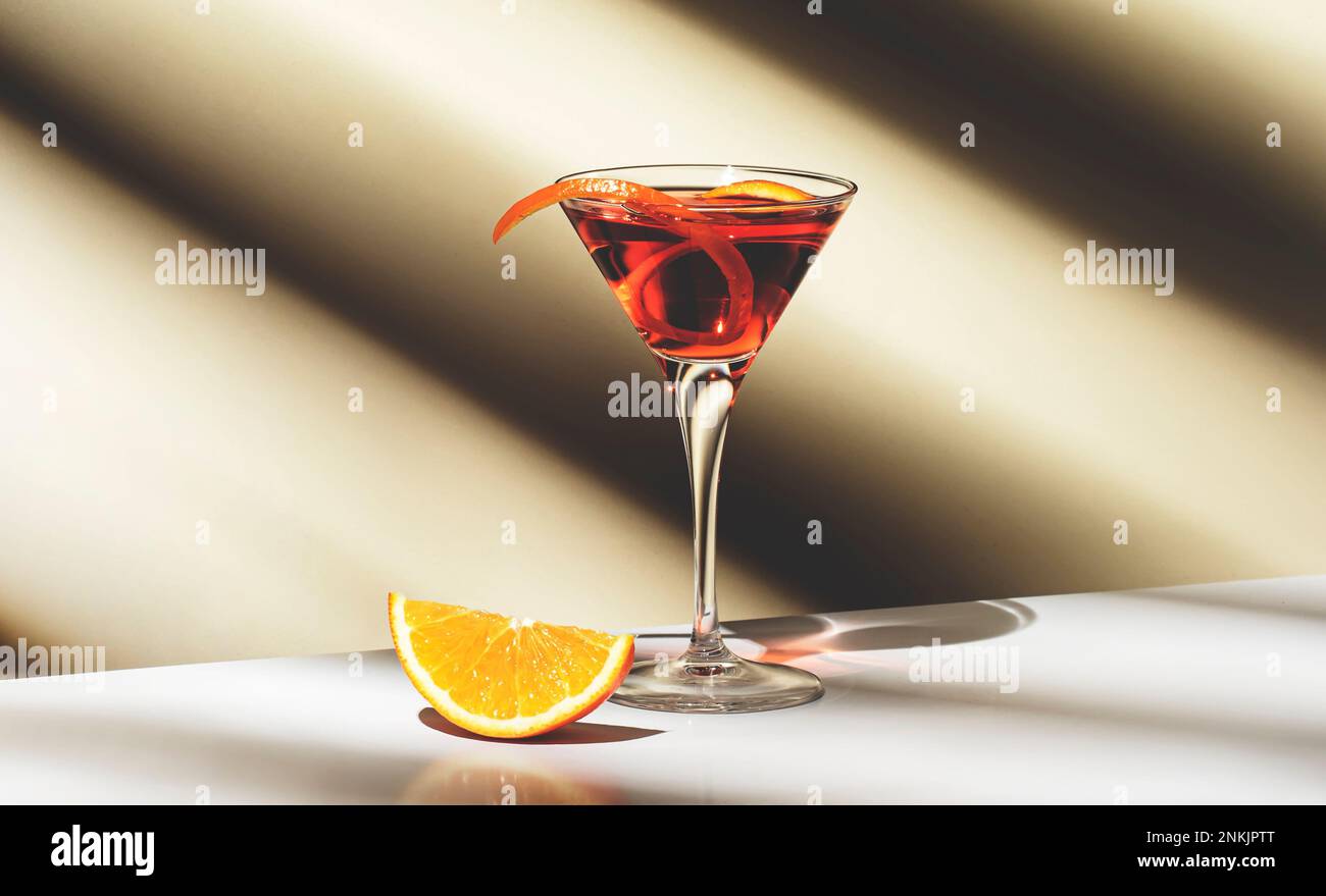 Boisson alcoolisée Martinez avec vermouth rouge, liqueur, orange amer, zeste et glace. Fond beige clair, lumière dure, motif ombre, copie sp Banque D'Images